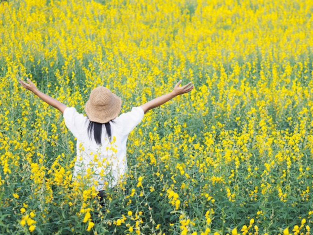 Femme levant les bras et debout dans le champ.