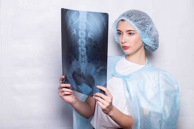 Femme levant la main et tenant un médicament de médecin d'image radiographique, le docteur examine l'image radiographique. Une femme portant un masque de protection et un costume lève ses lunettes avec sa main et tient un instantané des poumons.