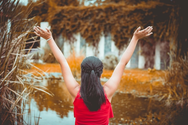 Femme levant ses mains devant un lac