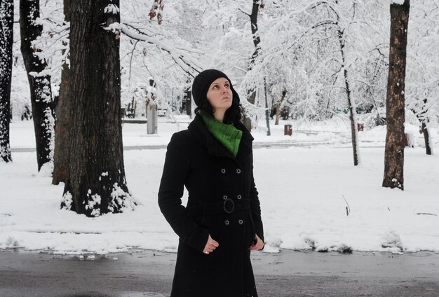 Photo femme levant les yeux alors qu'elle se tient sur une route couverte de neige