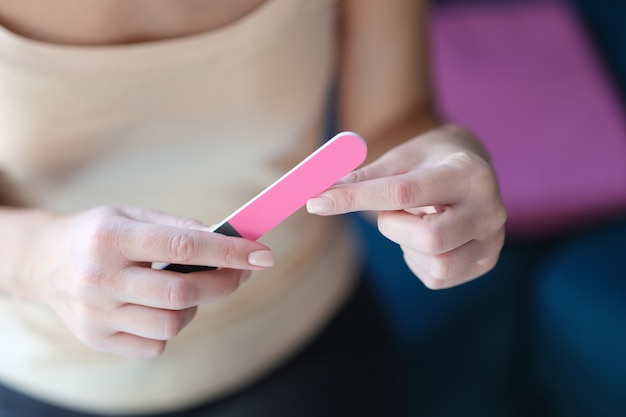 La femme lime les ongles avec une lime à ongles rose. Choisir un concept de lime à ongles de qualité fiable