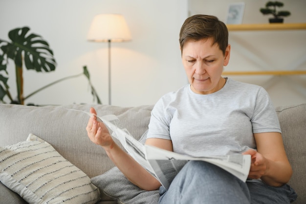 Femme lisant le journal à la maison