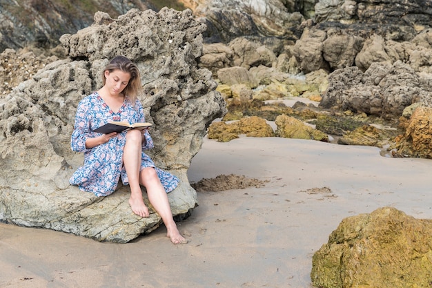 Femme Lisant Un Livre Assis Sur Un Rocher Sur La Plage