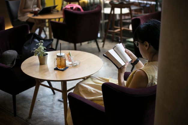 Femme lisant un livre assise dans un café