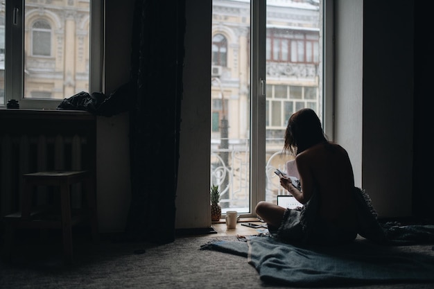 Photo femme lisant un livre assise sur le sol à la maison