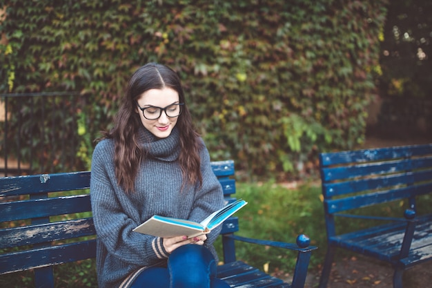 Femme lisant un livre sur le banc dans un parc