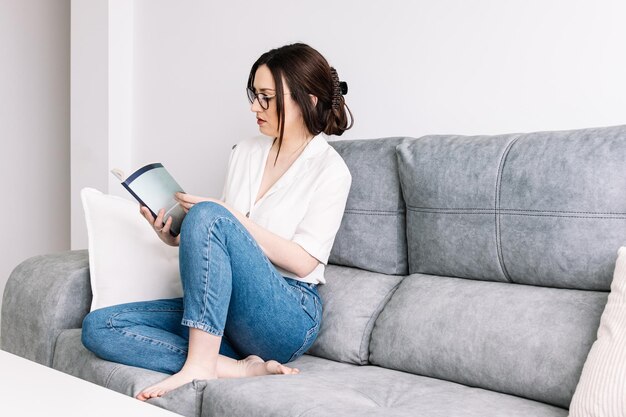 Femme lisant un livre sur le canapé