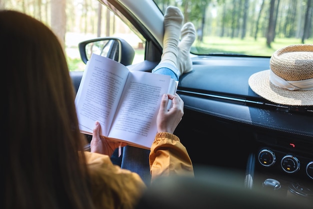 Une femme lisant un livre en conduisant la voiture