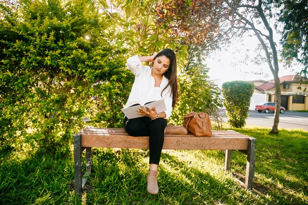 Femme lisant un livre dans un banc du parc