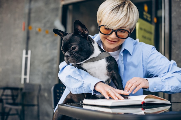 Femme lisant un livre dans un café avec son animal de compagnie bouledogue français