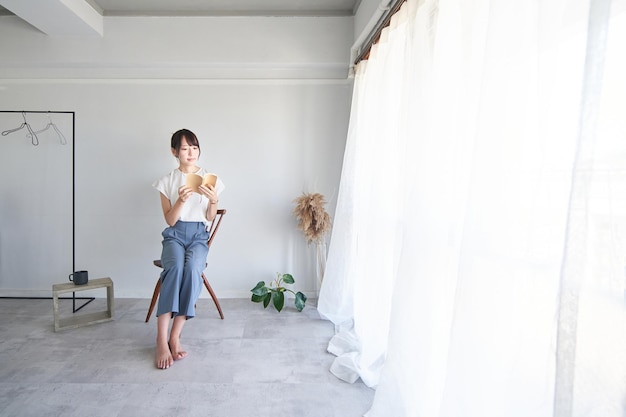 Une femme lisant un livre dans une chambre simple