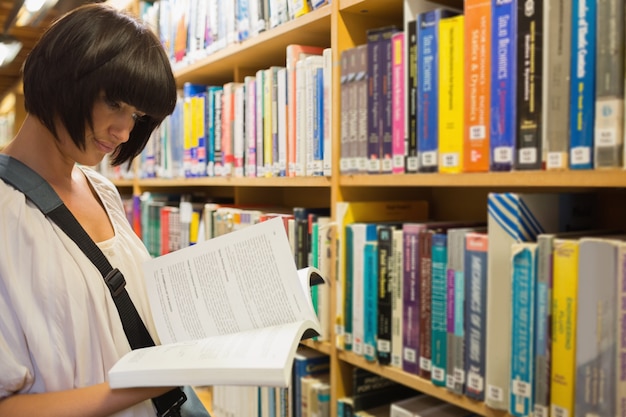 Femme lisant un livre devant une étagère