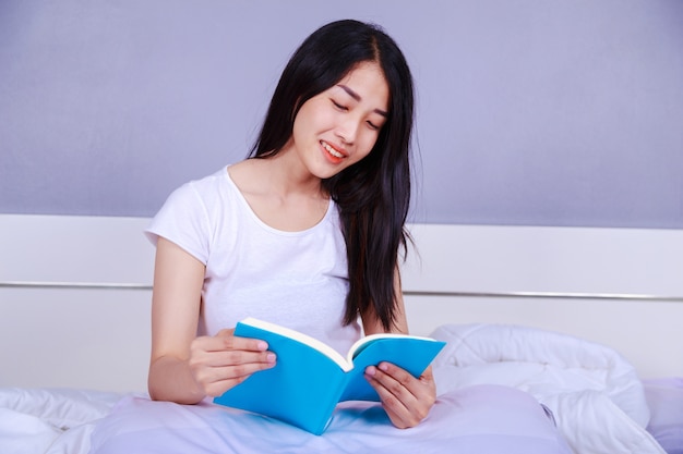 femme lisant un livre sur le lit dans la chambre à la maison