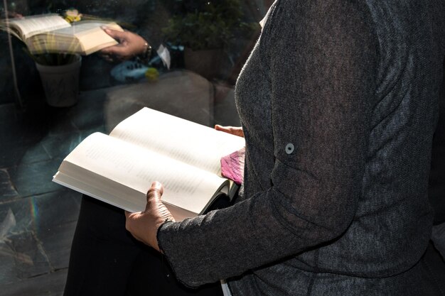 Femme lisant un livre près de la fenêtre.