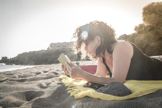 Photo femme lisant un livre en se relaxant sur la plage