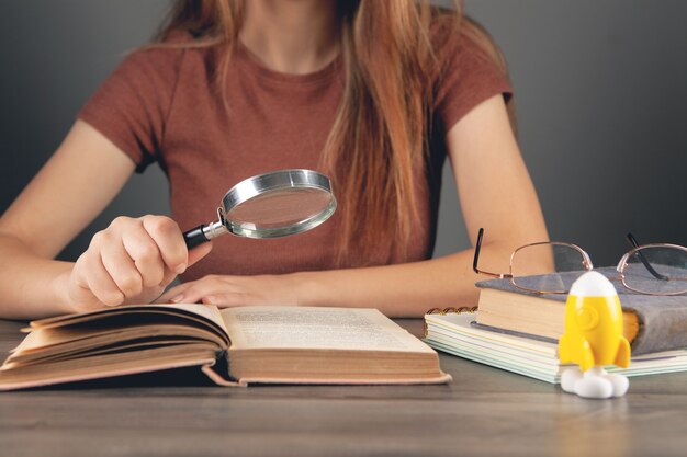 Photo femme lisant un livre à la table avec une loupe