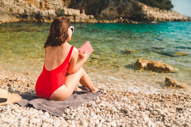 Femme lisant un livre en vacances d'été sur la plage de la mer