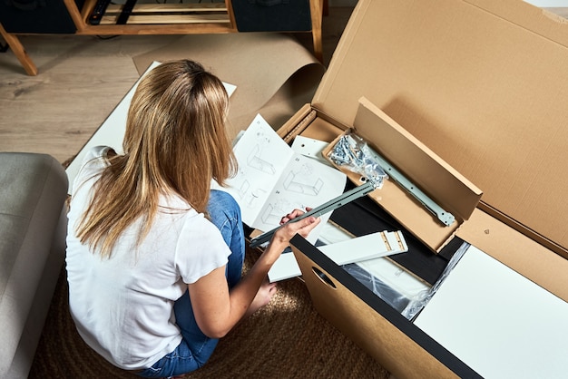 Femme lisant un manuel d'instructions pour assembler des meubles