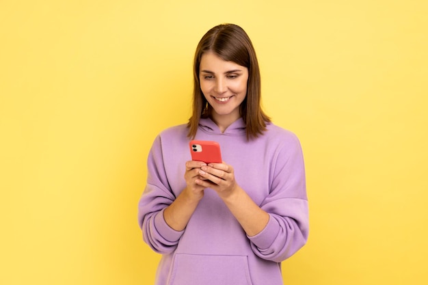 Femme lisant un message sur un smartphone et souriant à l'aide d'un appareil mobile pour la communication