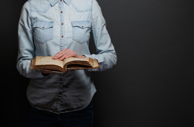 Femme lisant une vieille Bible sur fond gris