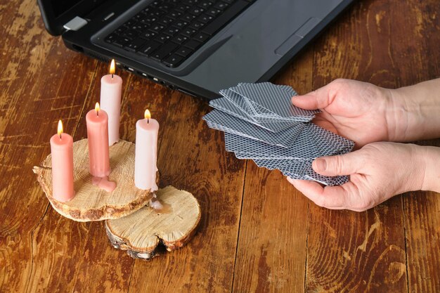 Une femme lit des cartes devant un ordinateur bougies un ordinateur portable jouant aux cartes divination sur Internet