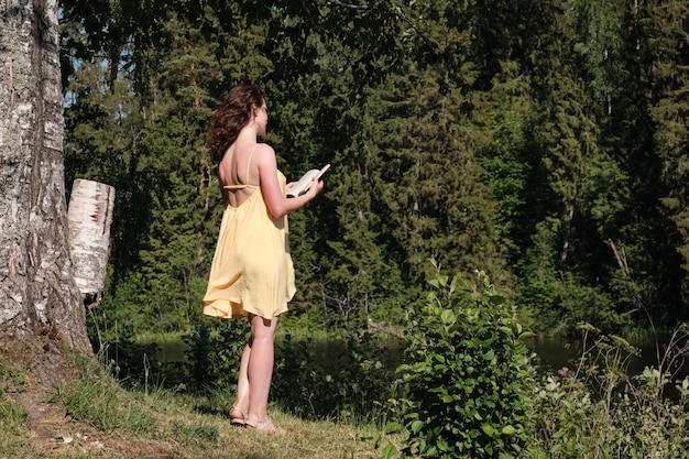 Une femme lit un livre au bord du lac