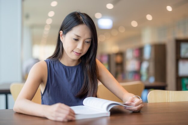 Une femme lit le livre à la bibliothèque.