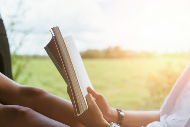 Une femme lit un livre dans un magnifique parc et un étang, se détend et se fond dans un environnement paisible.