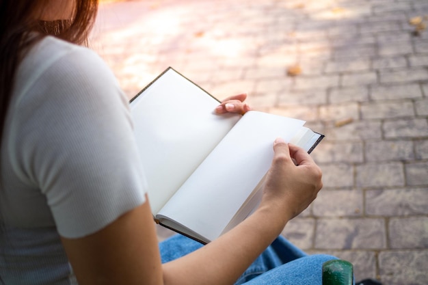 Une femme lit un livre dans le parc Apprendre et rechercher assidûment des connaissances tout le temps