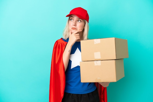 Femme de livraison caucasienne de super héros isolée sur fond bleu ayant des doutes