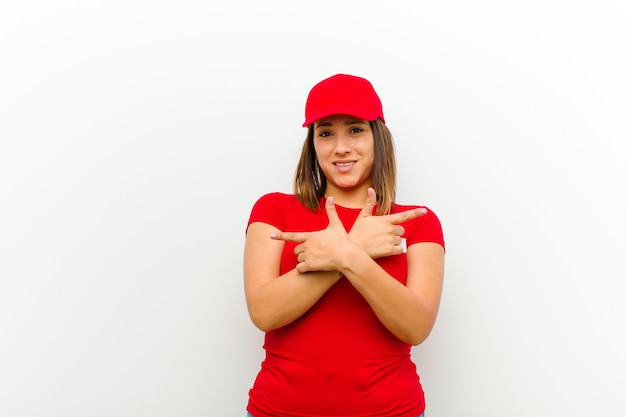 Femme de livraison à la recherche perplexe et confuse, peu sûre et pointant dans des directions opposées avec des doutes sur fond blanc