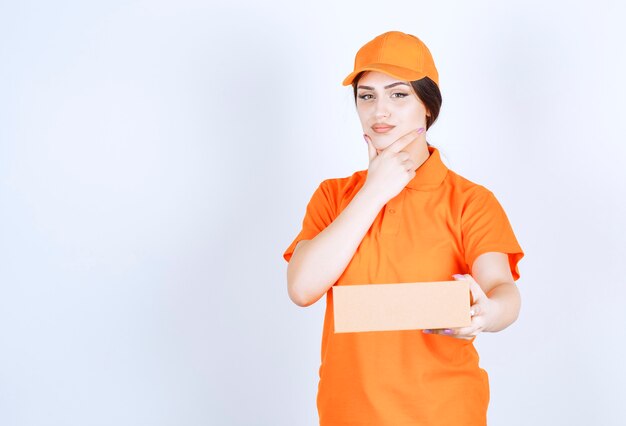 Femme de livraison réfléchie sur mur blanc