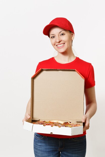 Femme de livraison en uniforme rouge isolé sur fond blanc. Jolie femme en casquette, t-shirt, jeans travaillant comme coursier ou revendeur tenant une pizza italienne dans une boîte plate en carton. Copiez l'espace pour la publicité.