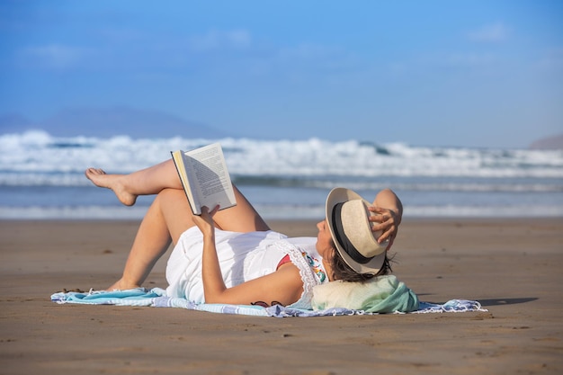 Femme avec livre froid près de la mer