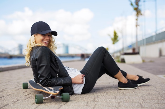 Femme avec longboard assis sur le sol