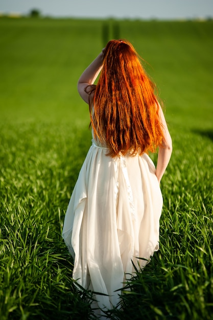 Femme en longue robe blanche sur un champ vert