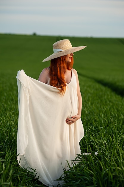 Femme en longue robe blanche sur un champ vert