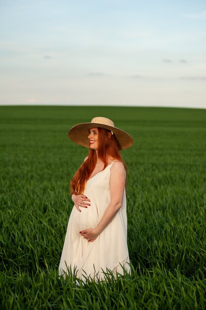 Femme en longue robe blanche sur un champ vert