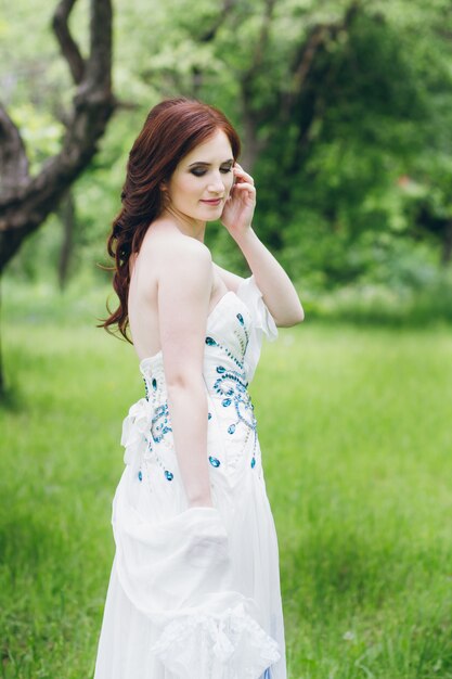 Femme en longue robe blanche dans le jardin d'été