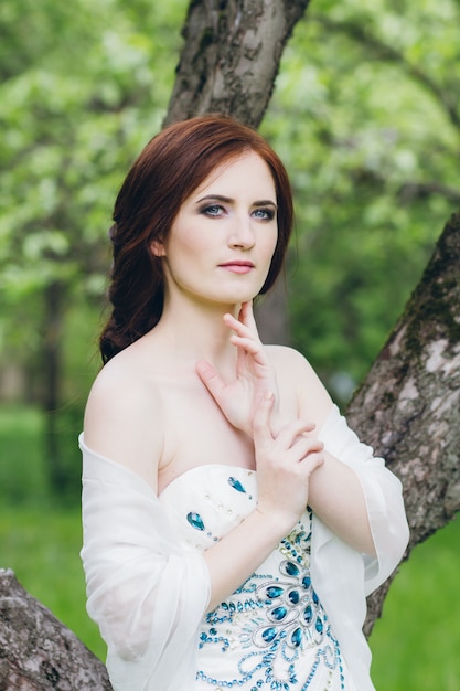 Femme en longue robe blanche dans le jardin d'été