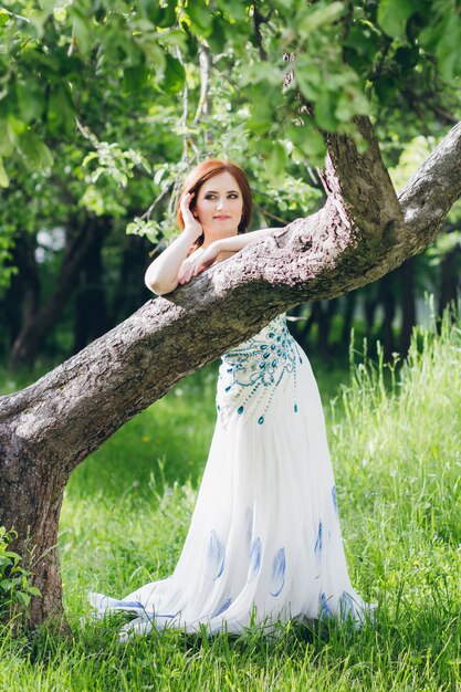 Femme en longue robe blanche dans le jardin d'été