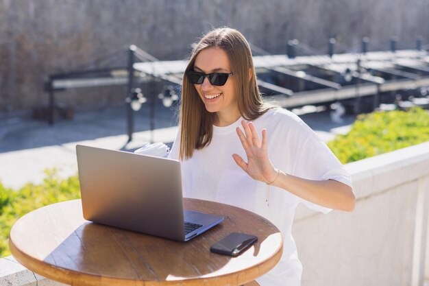 Une femme lors d'un appel professionnel avec des partenaires de la terrasse du café Travail à distance Résoudre à distance les problèmes de l'entreprise