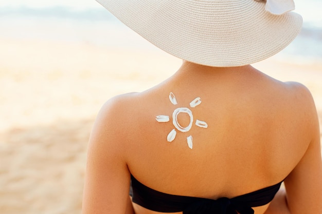 Femme avec une lotion solaire en forme de soleil