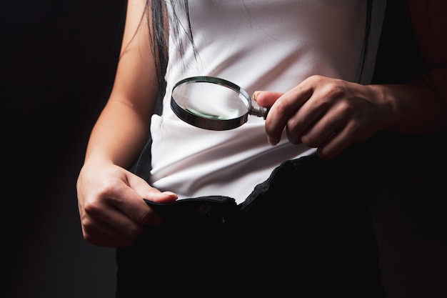 Une femme avec une loupe examine l'entrejambe derrière un jean