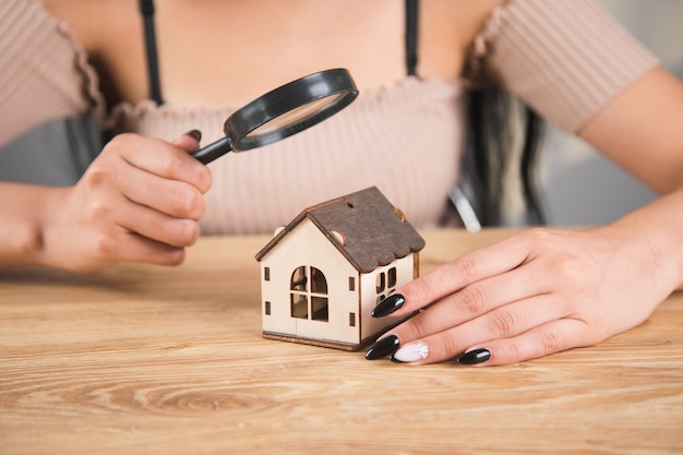 Une femme avec une loupe regarde la maison. concept de recherche à domicile