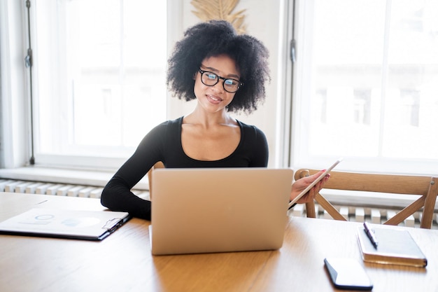 Une femme avec des lunettes au bureau travaille sur un projet de démarrage à l'aide d'un ordinateur portable