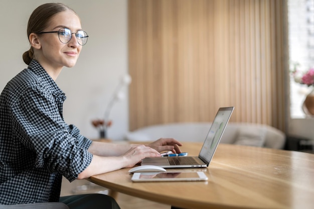 Une femme à lunettes est une économiste indépendante qui travaille utilise un ordinateur portable et fait un rapport