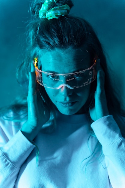 Femme avec des lunettes futuristes gesticulant sur un portrait de fond bleu à la recherche