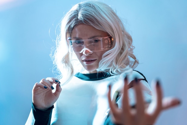 Femme avec des lunettes futuristes illuminées et une réalité virtuelle de cheveux blancs avec un regard sérieux