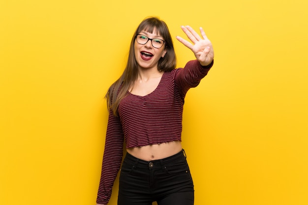 Femme à lunettes heureuse et comptant quatre avec les doigts